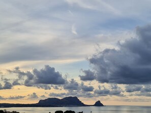 A coastal landscape with mountains in the distance and a body of water in the foreground. - Burdi House Apartment Surrounded by Greenery and Tranquility Near the sea (Altavilla Milicia)
