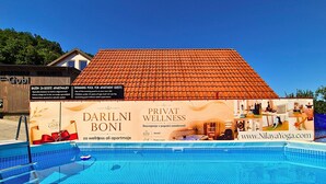 A swimming pool with a tiled roof and a wall advertisement for Darilni Boni Private Wellness. - Olimje Apartment with Private Sauna & Free Outdoor Pool - Gobi (Šmarje pri Jelšah)