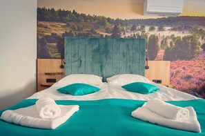 Une chambre d’hôtel avec un lit, deux oreillers, une tête de lit et un climatiseur fixé au mur.