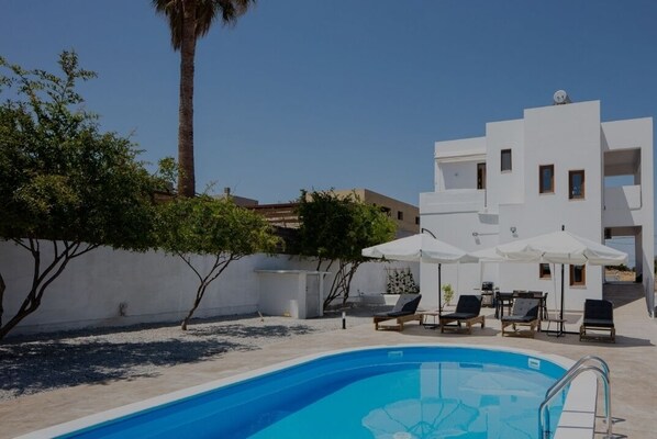 A modern pool area with a clear blue pool, white umbrellas, and lounge chairs. - Vedema Villas Skaleta (Σκαλέτα)