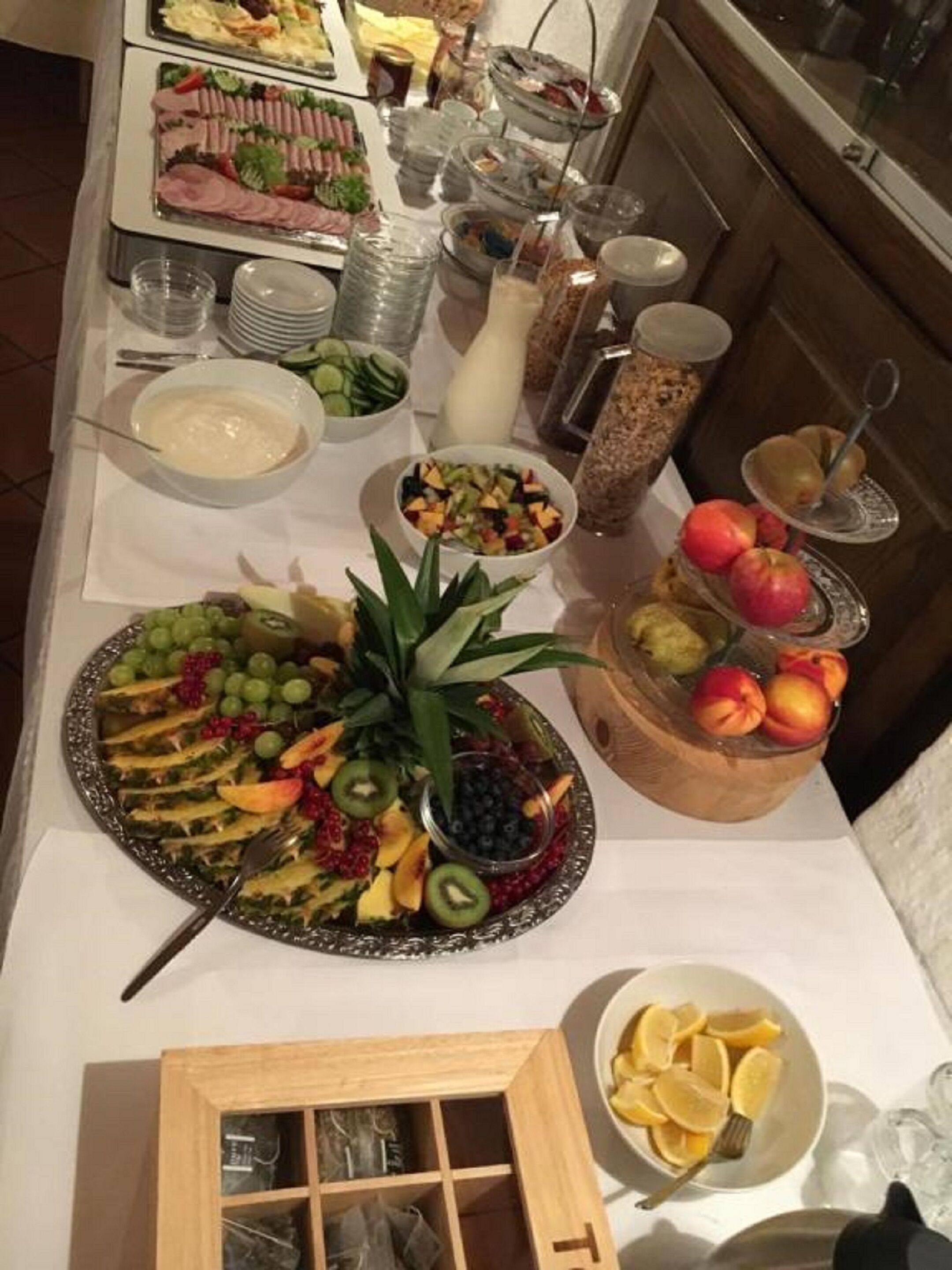 A buffet table with various food items including fruits, salads, and a selection of meats.