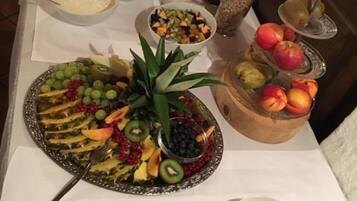 A buffet table with various food items including fruits, salads, and a selection of meats.