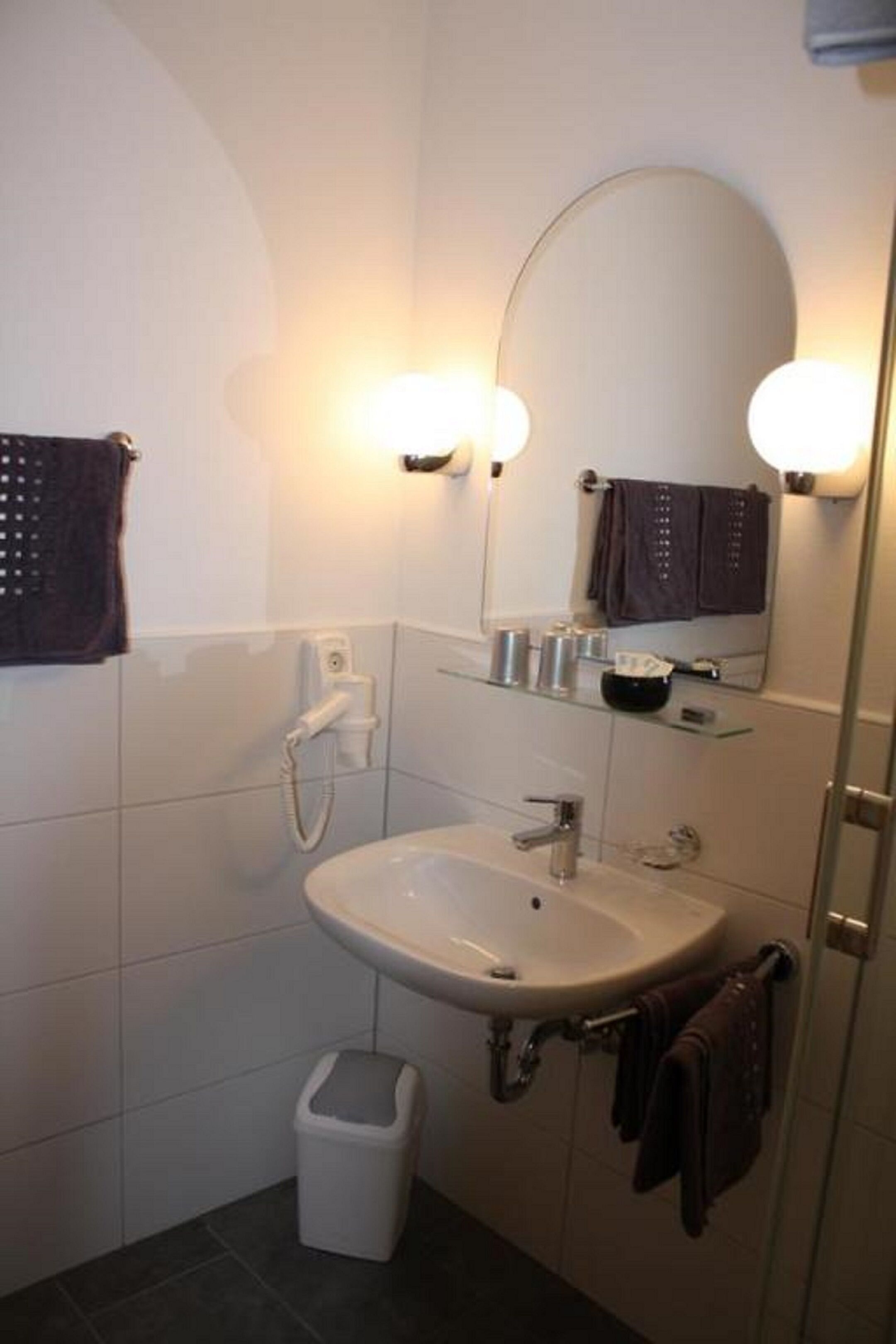 Une salle de bain avec un lavabo blanc, un miroir et un porte-serviettes.