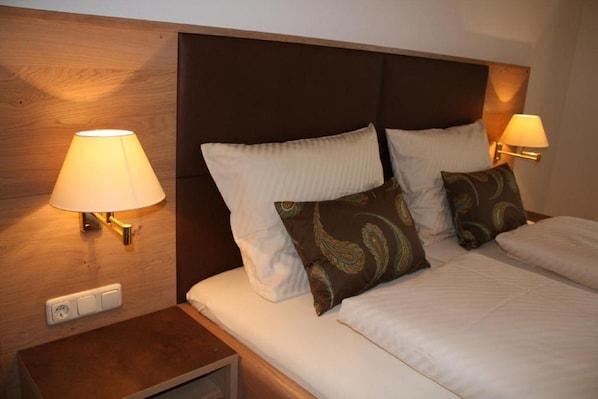 Una habitación de hotel con una cama grande, dos lámparas de noche y un cabecero de madera.