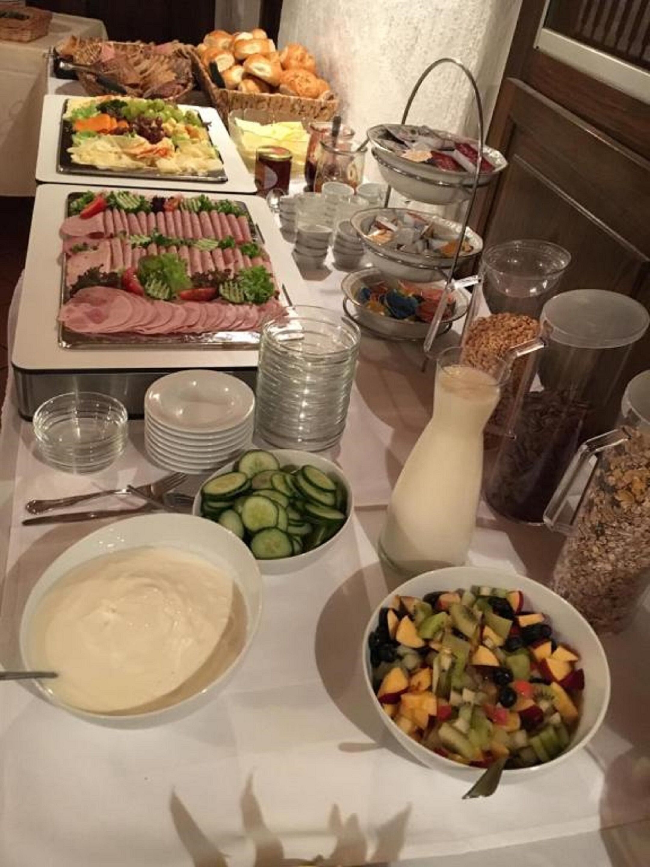 A buffet table with various food items including sliced meats, salads, and fruits.