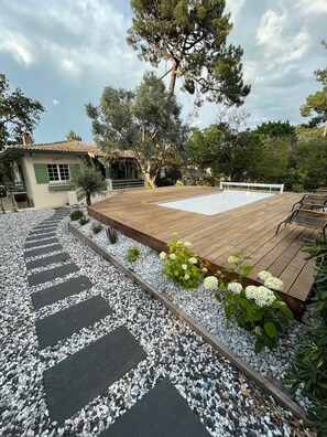 A wooden deck with a pool, surrounded by a pebble path and greenery. - Villa Arcachon/abatilles Piscine / Lisière Foret (Arcachon)