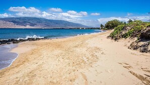 A beach with a clear view of the ocean and distant mountains. - Newly Remodeled Steps to Sugar Beach! (Kihei)