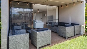 An outdoor patio with wicker furniture and string lights. - Newly Remodeled Steps to Sugar Beach! (Kihei)