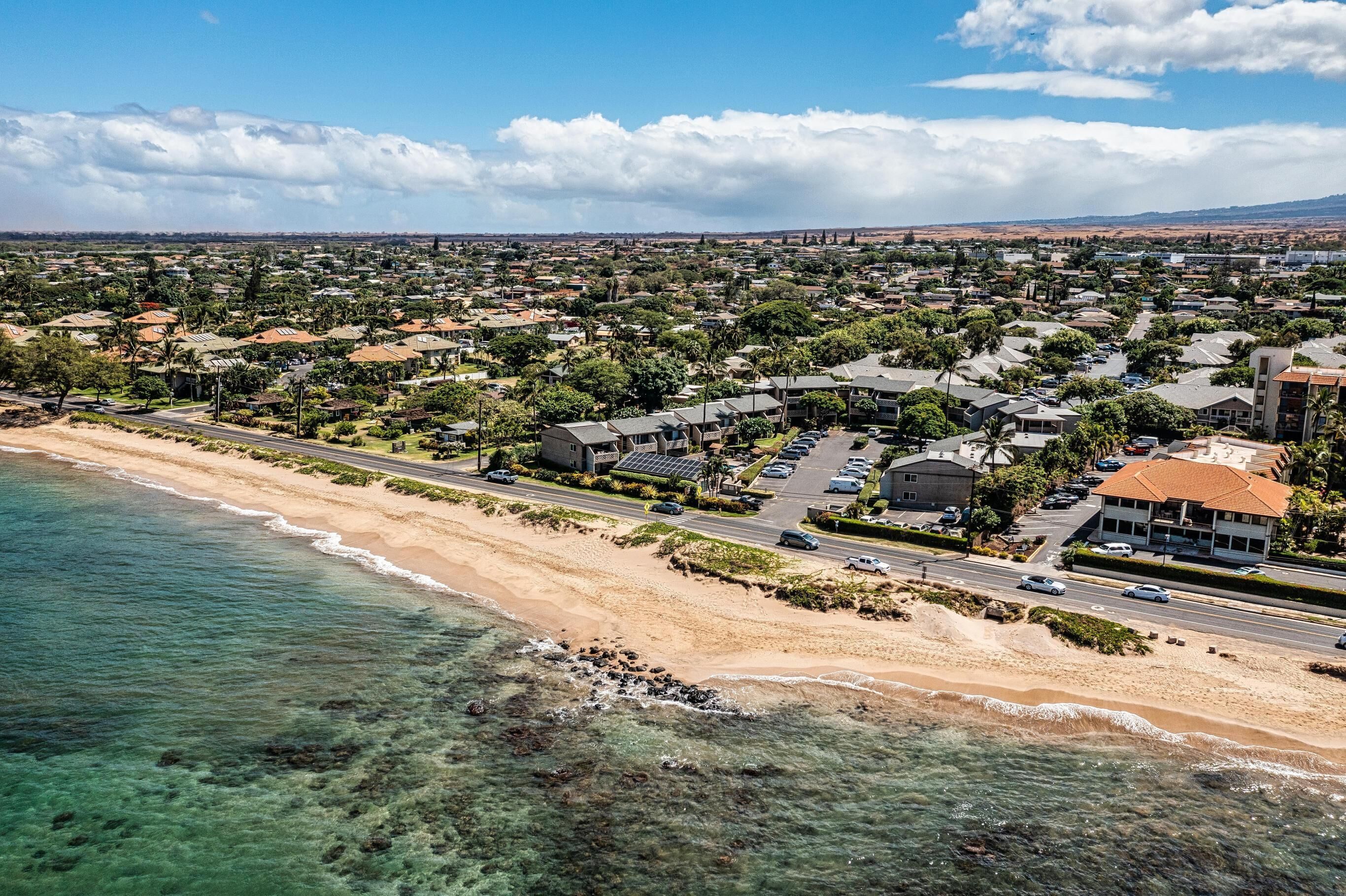 Vue aérienne d’une ville côtière avec une plage, des routes et des immeubles d’habitation.