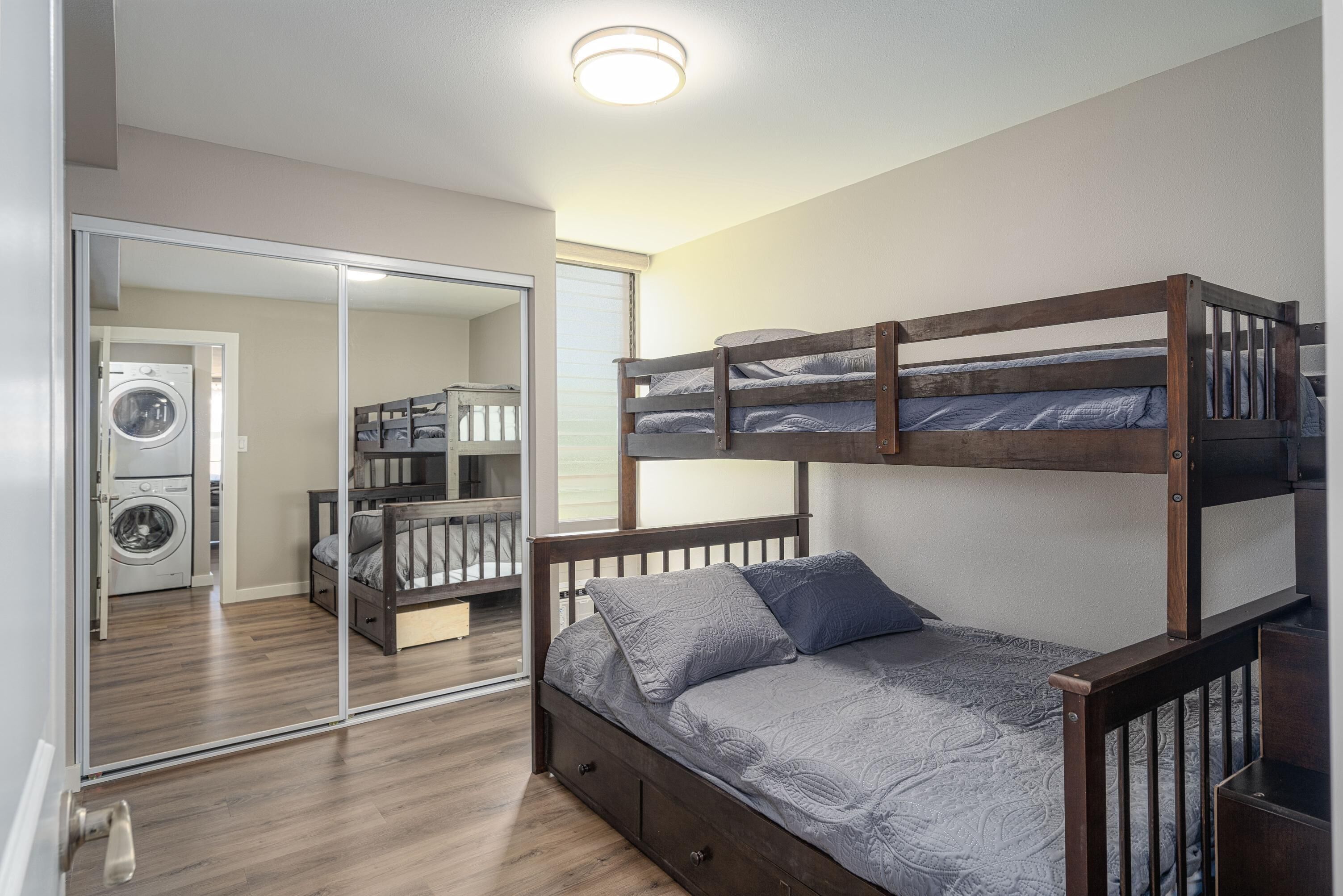 A bunk bed with a wooden frame and a lower bed with a patterned bedspread.