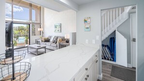 Une cuisine moderne dotée d’un plan de travail en marbre, d’un coin repas avec un canapé et d’un escalier menant à une mezzanine.