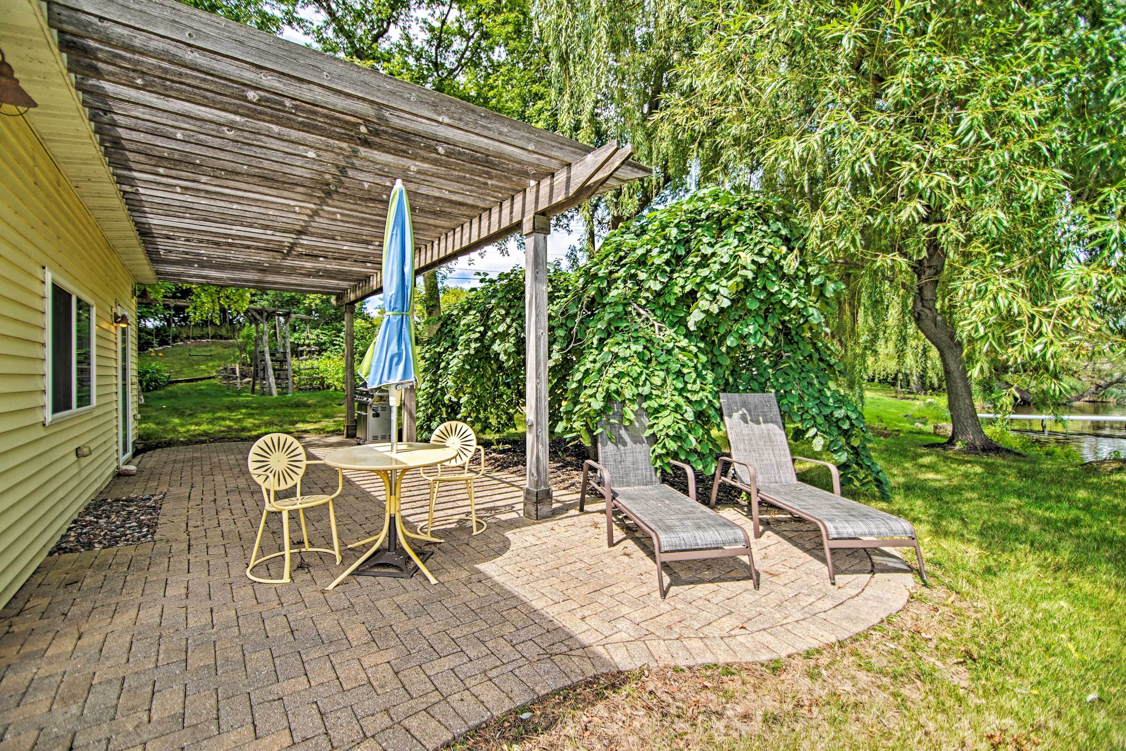 A patio area with a covered seating area, a table with chairs, and a lounge chair.