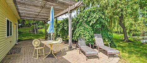A patio area with a covered seating area, a table with chairs, and a lounge chair.