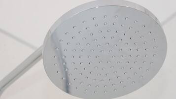 Un objeto metálico circular y perforado, probablemente un cabezal de ducha, sujeto a una estructura blanca.