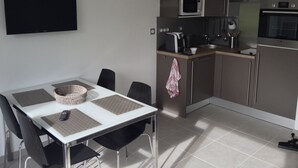 A modern kitchen with a dining area, including a flat-screen TV, a microwave, a coffee maker, and a sink. - GITE ET SPA LES CABANES 1 à 4 PERS, BAIE DE SOMME (Grand Laviers)