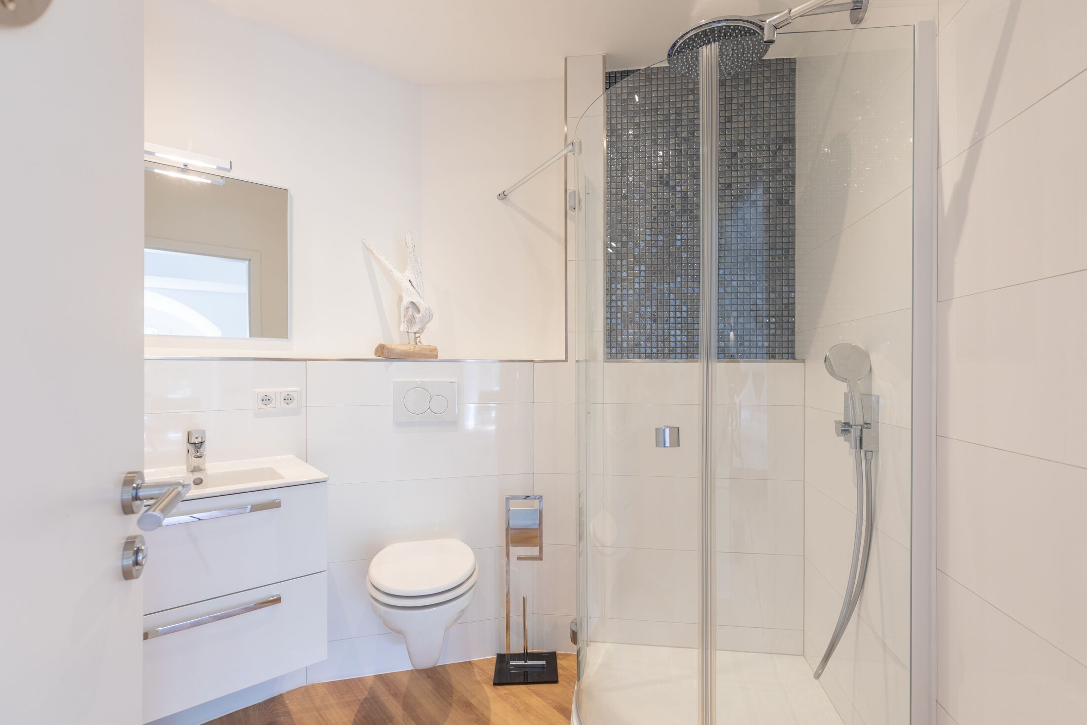A modern bathroom with a glass-enclosed shower, a white toilet, and a vanity with a mirror.
