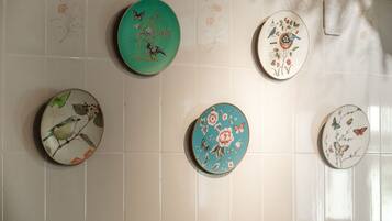Una pared con cinco platos de cerámica decorados con diseños de pájaros y flores.