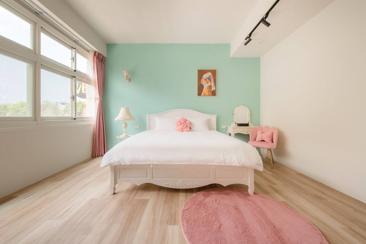 A bedroom with a bed, a chair, a lamp, and a painting on the wall.