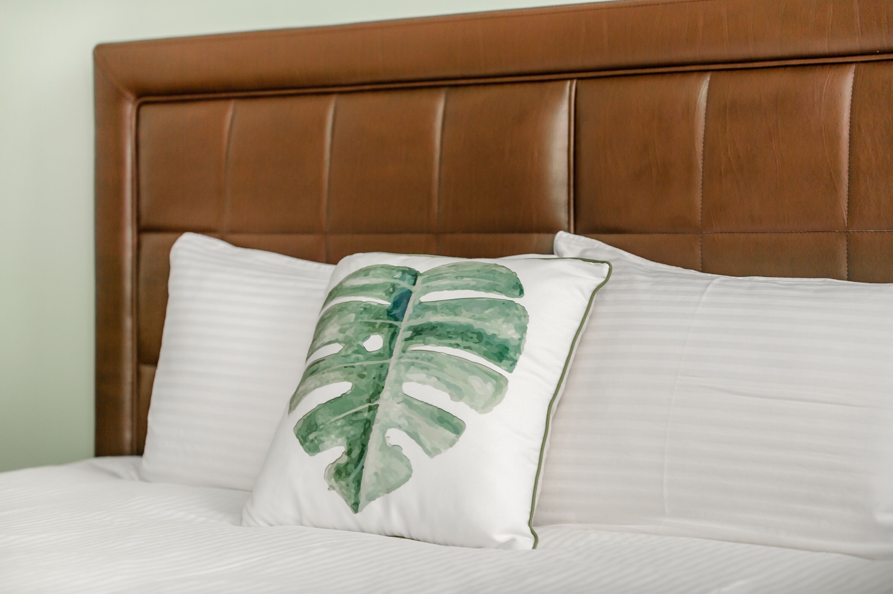Una cama con cabecera marrón y ropa de cama blanca.