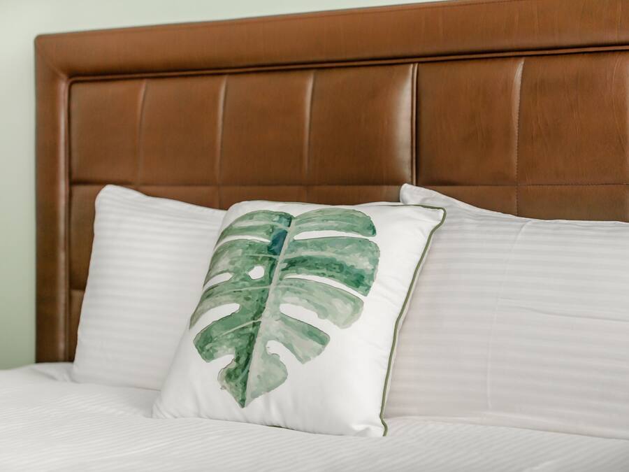 Una cama con cabecera marrón y ropa de cama blanca.