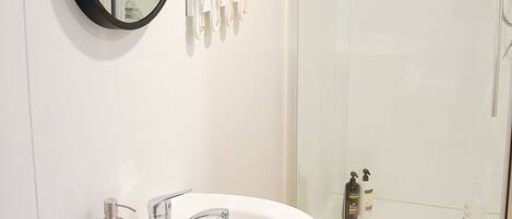 A bathroom with a white sink, a mirror, and a glass shower enclosure.