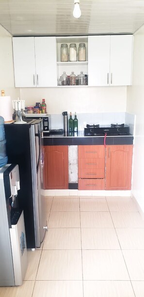 A kitchen with white cabinets, a black countertop, and a tiled floor.