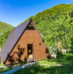 A wooden cabin with a sloped roof, a small porch, and a door leading to an interior space.