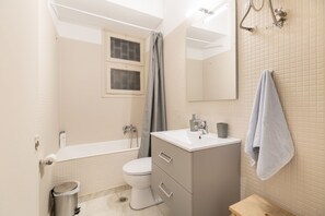 A modern bathroom with a bathtub, toilet, vanity, and a mirror. - Bang in Kolonaki by Athenian Homes (Athens)