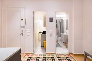 A hotel room with a large mirror, a bed, a desk, and a bathroom visible through an open door. - Bang in Kolonaki by Athenian Homes (Athens)