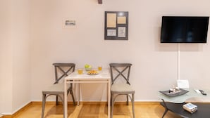 A dining area with two chairs, a table, and a TV mounted on the wall. - Bang in Kolonaki by Athenian Homes (Athens)