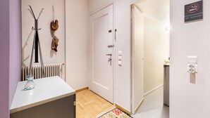 A hotel room with a white door, a radiator, a no smoking sign, and a small table with a vase. - Bang in Kolonaki by Athenian Homes (Athens)