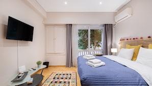 A modern hotel room with a large bed, a flat-screen TV, a desk with a computer, and a view of the outdoors. - Bang in Kolonaki by Athenian Homes (Athens)
