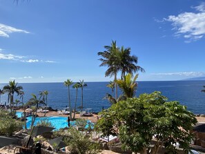 A pool area with lounge chairs and umbrellas, surrounded by palm trees and overlooking a body of water. - Las Flores studio 1 & FREE WIFI (Costa Adeje)