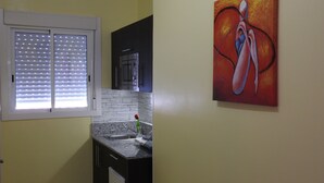 Una cocina con ventana, un lavamanos, una encimera y un cuadro en la pared.