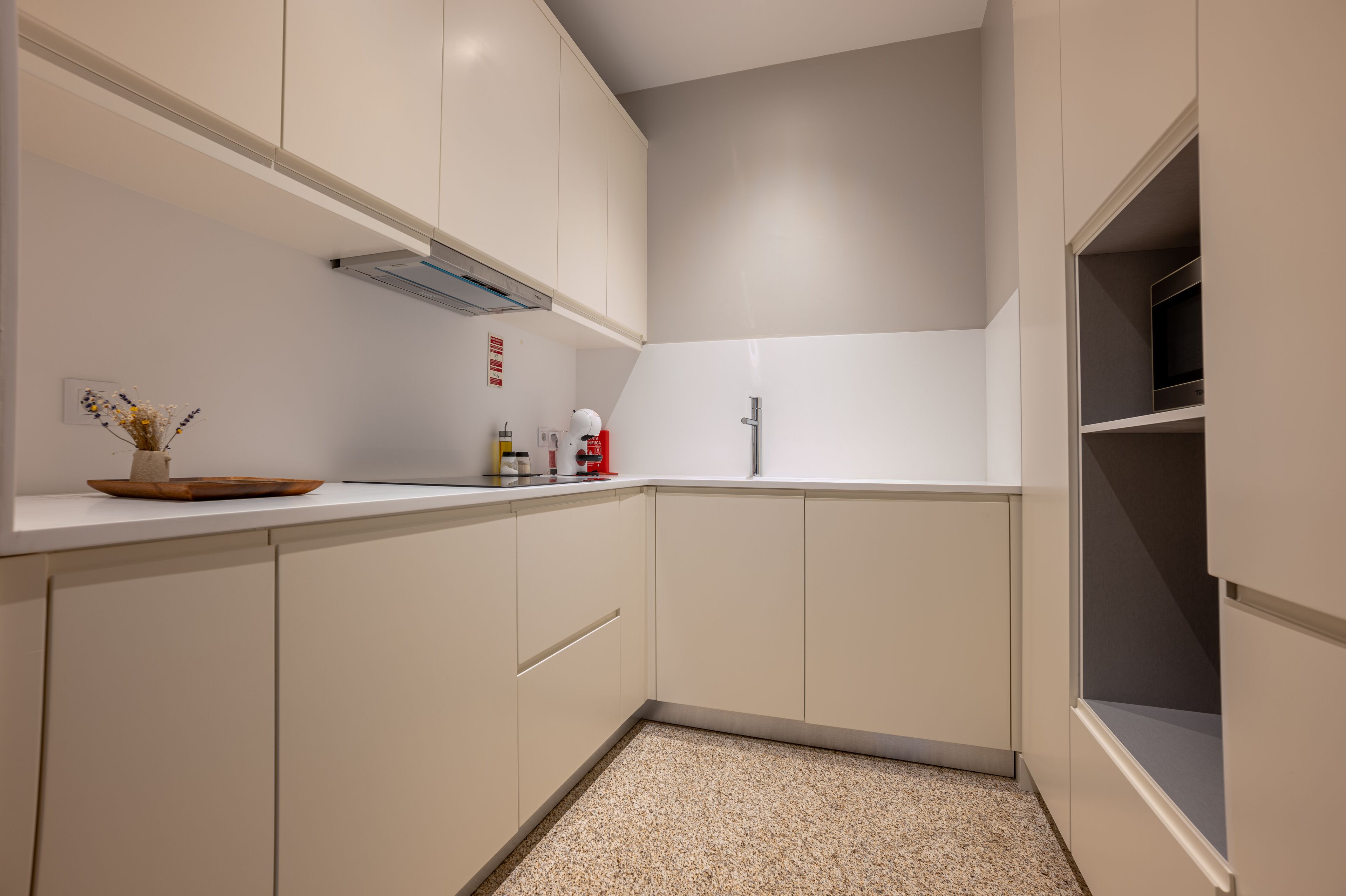 A modern kitchen with white cabinets, a stainless steel faucet, and a small countertop with a vase and kitchen items.