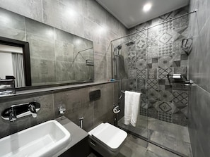 A modern bathroom with two sinks, a shower, and patterned tiles.