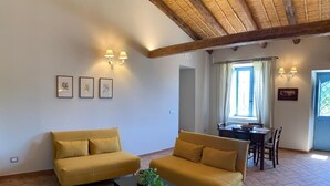 A living room with two yellow sofas, a coffee table, and a dining area with a table and chairs. - Masseria Santacatrini - Loft Nocellara (Melilli)