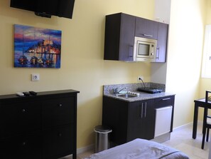 A compact kitchen with a microwave, sink, and a small cabinet. There's a painting on the wall and a trash can near the sink. - Las Flores studio 2 & FREE WIFI (Costa Adeje)