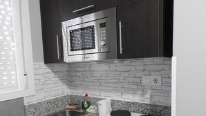 Une cuisine dotée de plans de travail en granit, d’un four à micro-ondes en acier inoxydable, d’un évier et d’une cuisinière.