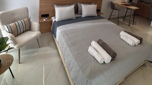 Moderni hotellihuone, jossa on suuri sänky, puinen pääty, työpöytä ja tuoli.