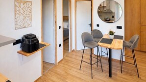 Moderni keittiö, jossa on ruokailutila, puulattia ja pieni jääkaappi.