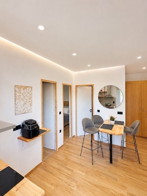 A modern kitchen with a dining area, wooden flooring, and a small refrigerator. - Jasmine by Checkin (Agios Nikolaos)