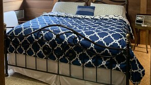 A bedroom with a wooden ceiling, a bed with a patterned bedspread, a ceiling fan, and a window with blinds. - Cozy House with Hot Tub (Macedon)
