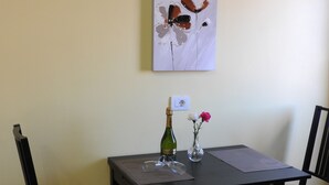 A dining table with a bottle of champagne, a glass, and a vase with flowers.