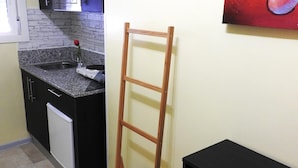 Une cuisine dotée d’un plan de travail en granit, d’un évier en acier inoxydable, d’un lave-vaisselle blanc et d’une chaise en bois.