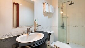 A bathroom with a white sink, a mirror, a toilet, and a glass-enclosed shower. - HANZ Boutique Hotel Ben Thanh (Ho Chi Minh City)