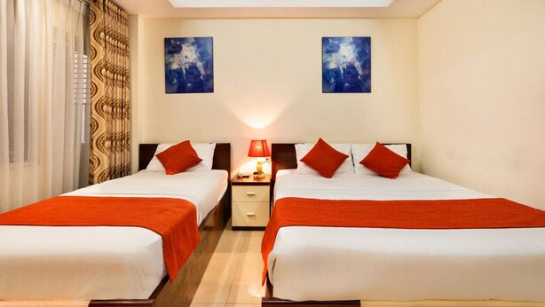 A hotel room with two beds, a nightstand, a lamp, and two paintings on the wall. - HANZ Boutique Hotel Ben Thanh (Ho Chi Minh City)