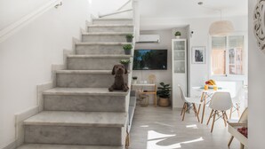 Eine Treppe führt zu einem Wohnbereich mit einem Fernseher, einem Esstisch und Stühlen.