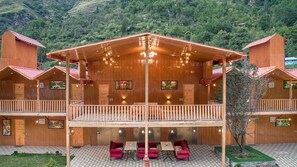 A wooden lodge with a balcony, multiple rooms, and a dining area with red sofas. - The Bright Side Resort (Banjar)