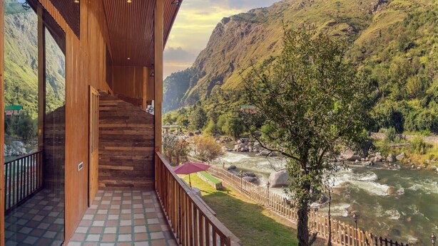 A wooden staircase leading to a balcony overlooking a river and mountains. - The Bright Side Resort (Banjar)